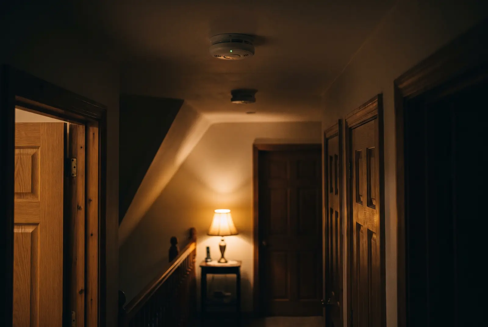 Two interlinked ceiling smoke alarms along an upstairs landing