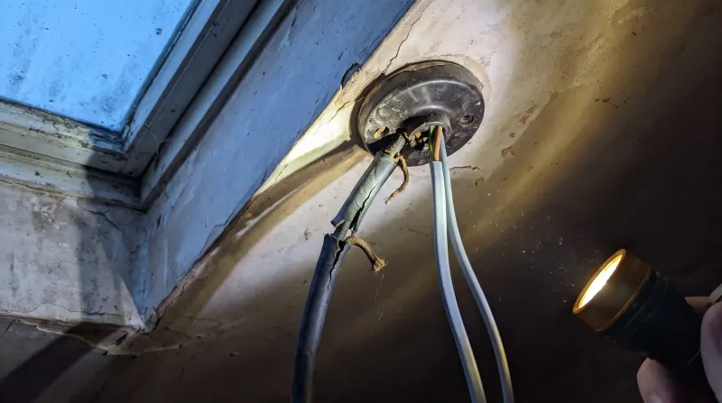 Perished rubber-sheathed cable exposed at a ceiling rose, found by an emergency electrician in Edmonton
