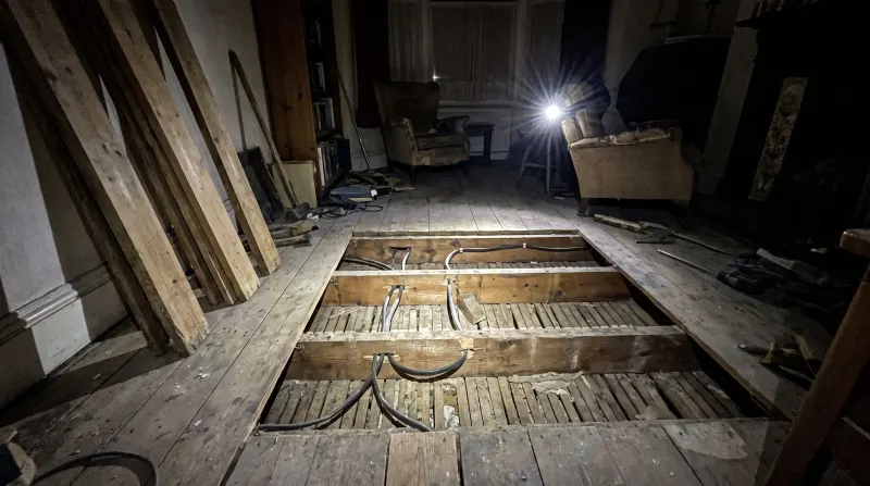 Cable runs notched through joists under lifted floorboards, found by an emergency electrician in Manor Park
