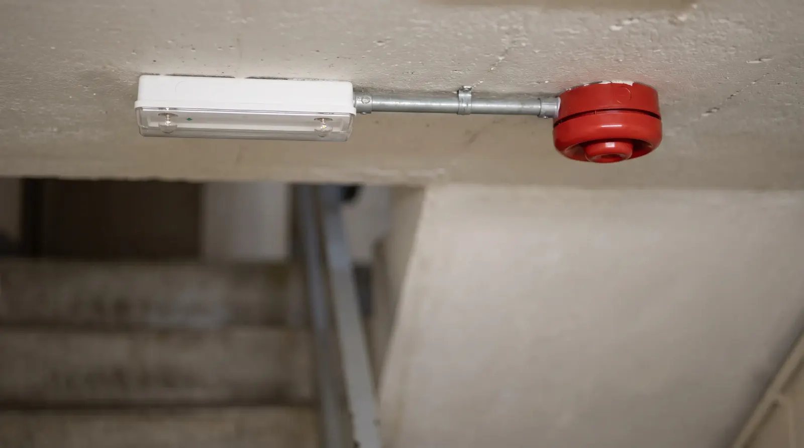 An emergency light and fire alarm sounder in a commercial stairwell — emergency lighting in Barking