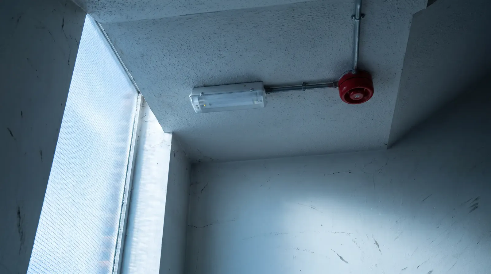 An emergency light and fire alarm sounder in a commercial stairwell — emergency lighting in Shoreditch