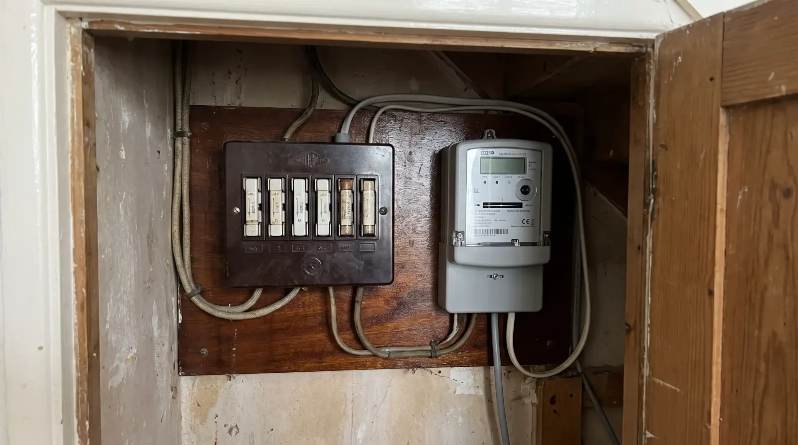 An original rewireable fuse box beside a newer meter — fuse board upgrade in Chingford