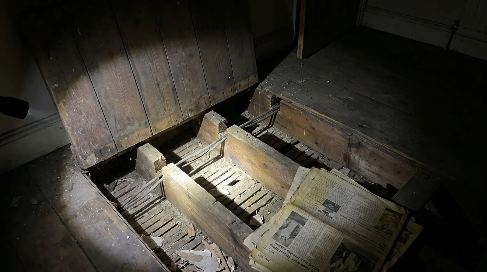 Cable runs notched through joists under lifted floorboards — house rewire in Sydenham