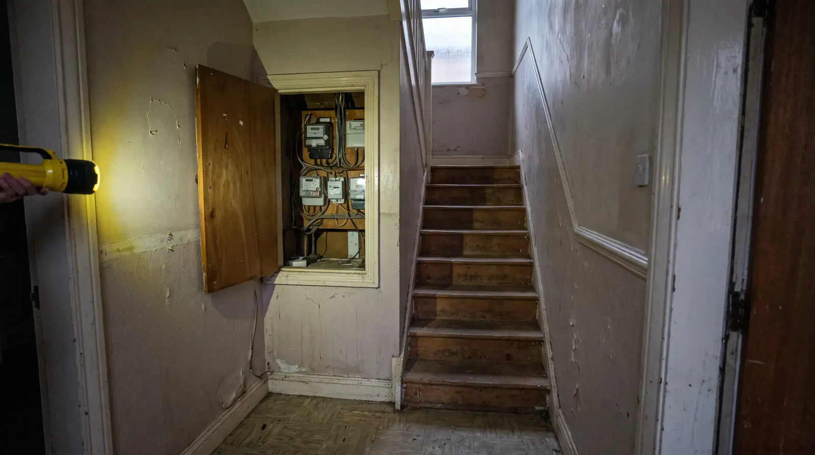 A stairwell to flats above a shop with the meter cupboard open — the kind of landlord electrics an electrician in Whitechapel is called out for