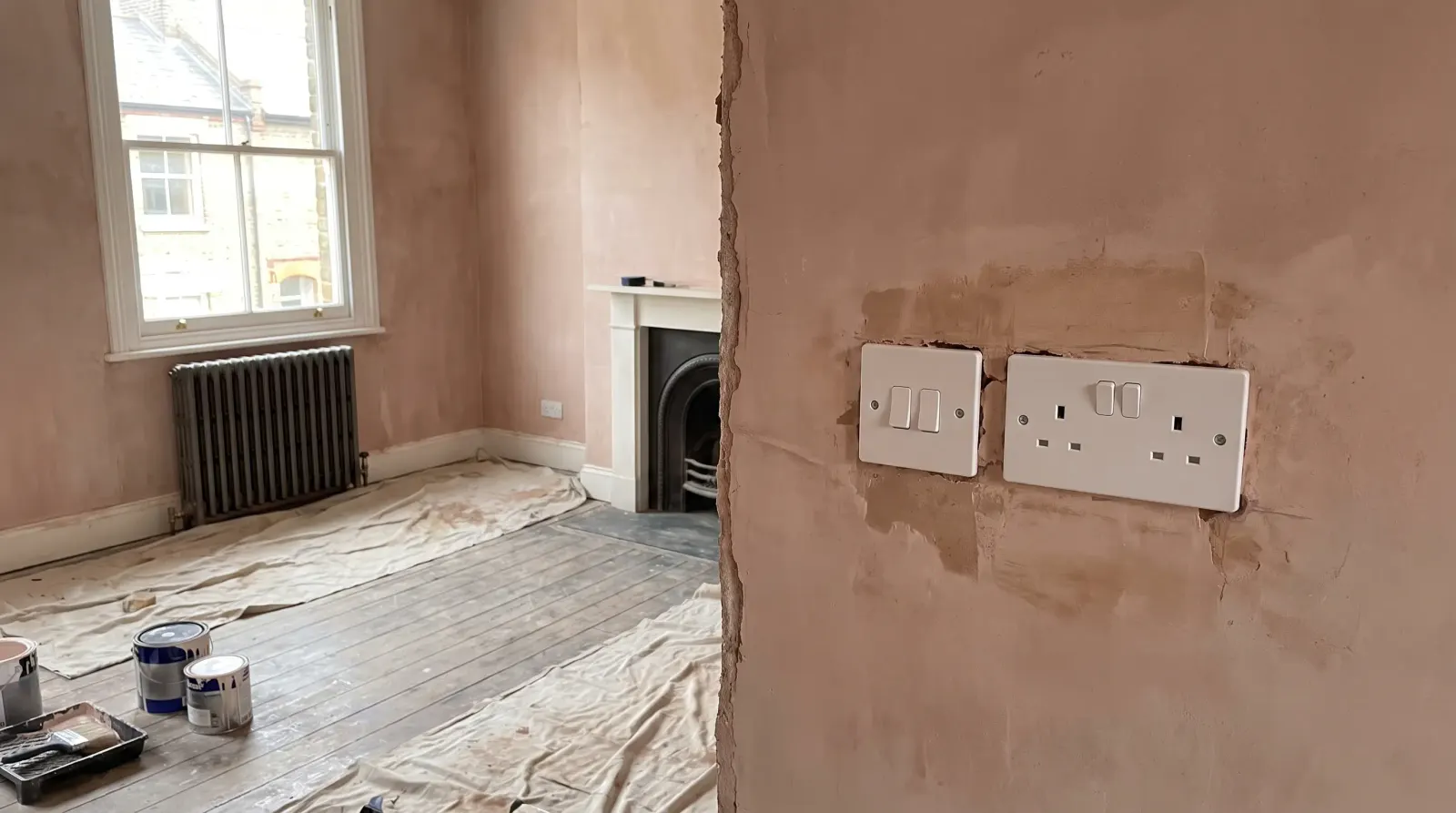 A new switch and socket on a replastered wall — the kind of new sockets and lighting an electrician in Bethnal Green is called out for