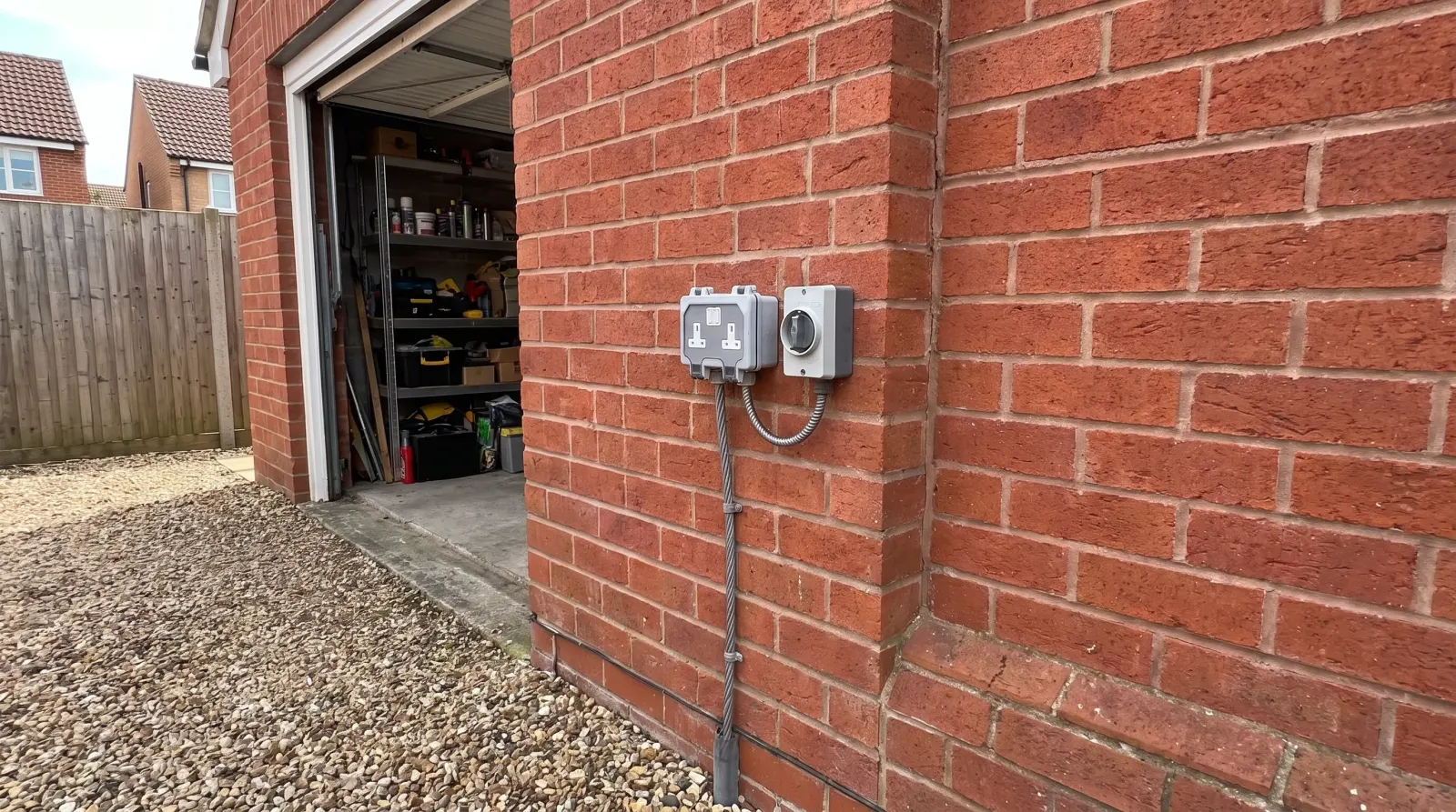 A weatherproof outdoor socket and isolator on a garage wall — outdoor sockets in Ongar