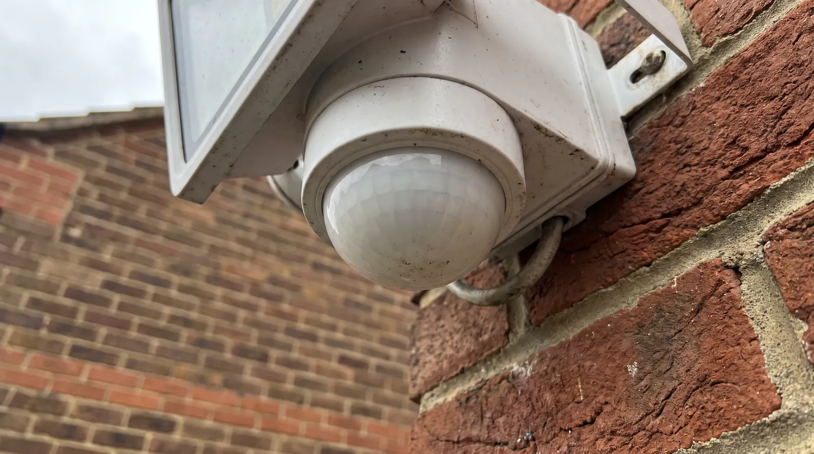The PIR sensor lens on the underside of a floodlight fitting, viewed close up