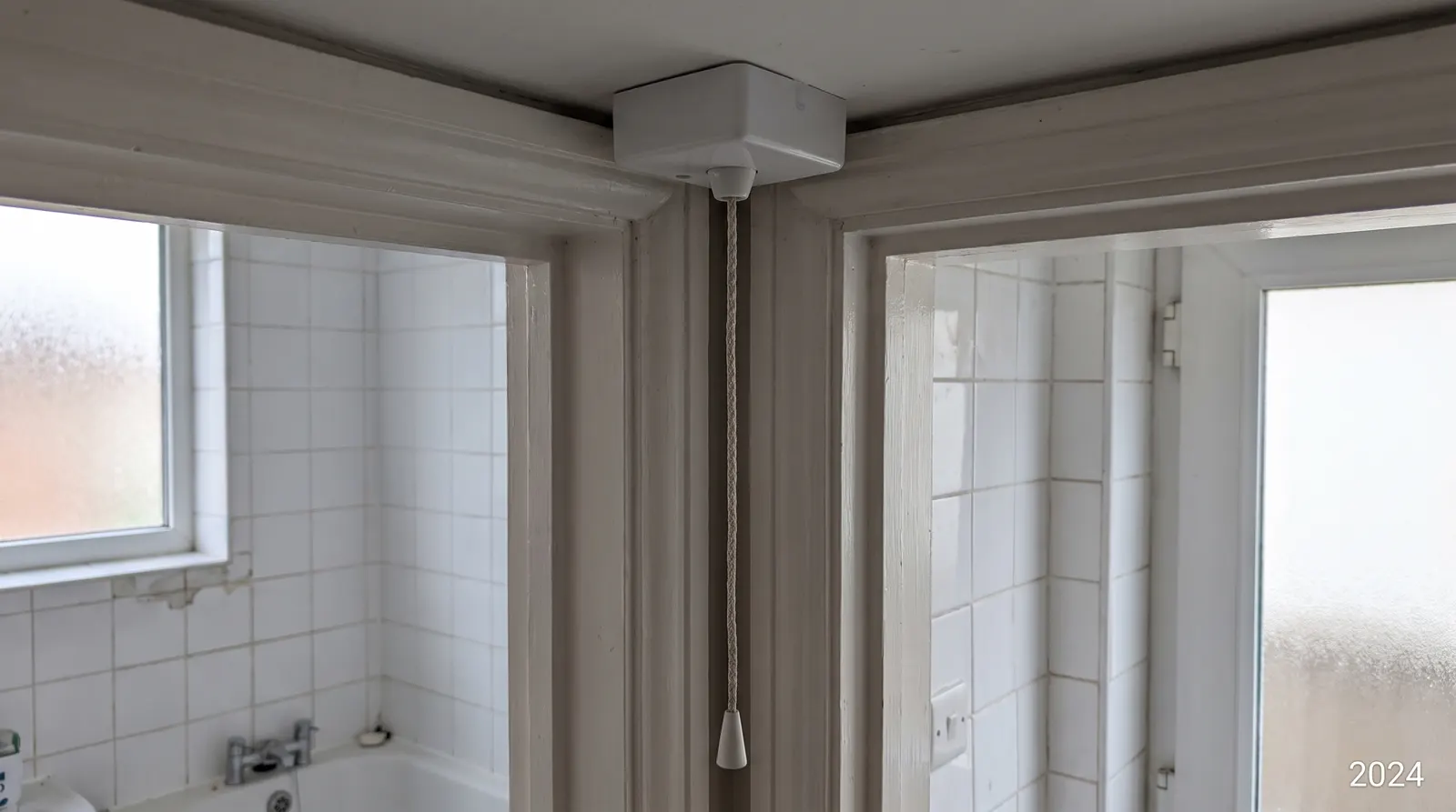 A ceiling-mounted pull cord light switch above a bathroom door