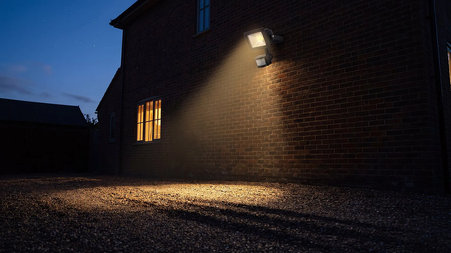 A PIR motion sensor mounted under the eaves of a house at dusk