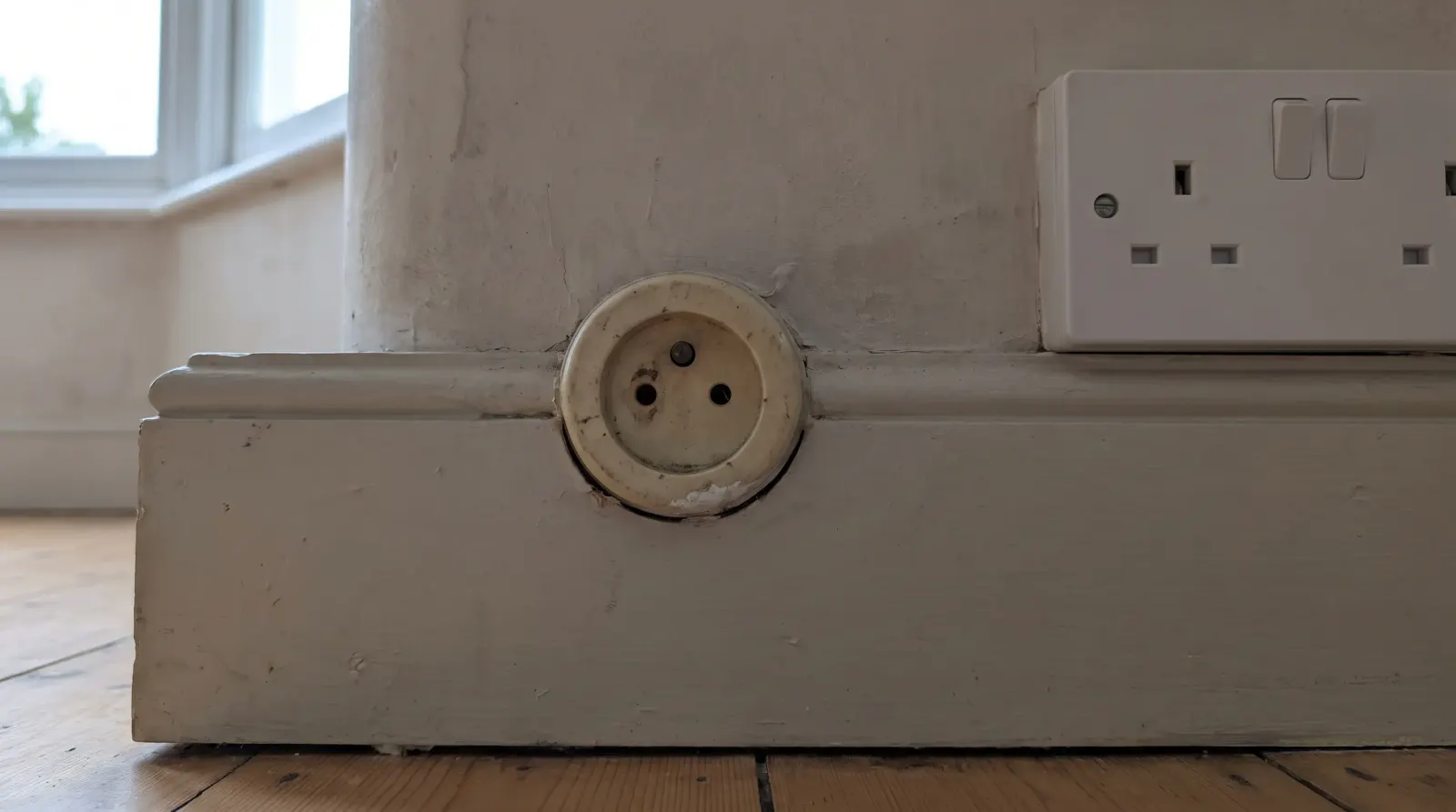 A surviving round-pin socket next to a modern three-pin one — the kind of new sockets an electrician in Catford is called out for