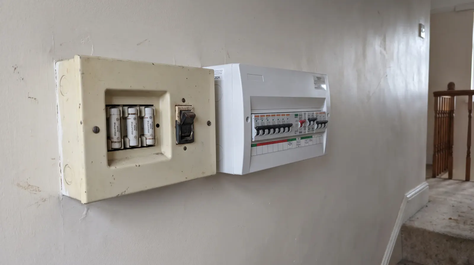 Two consumer units of different ages side by side on a landing — the kind of fuse board upgrade an electrician in Hackney is called out for