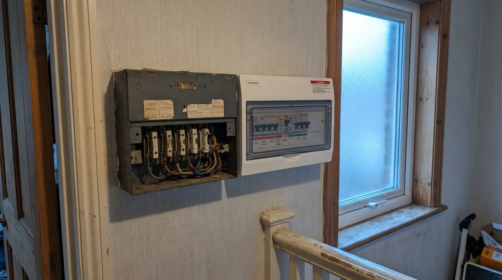 Two consumer units of different ages side by side on a landing — fuse board upgrade in New Cross