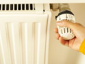 Hand turning a home radiator valve back on as the heating season begins