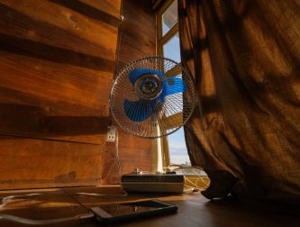 An electric fan and phone by a sunlit window during hot summer weather
