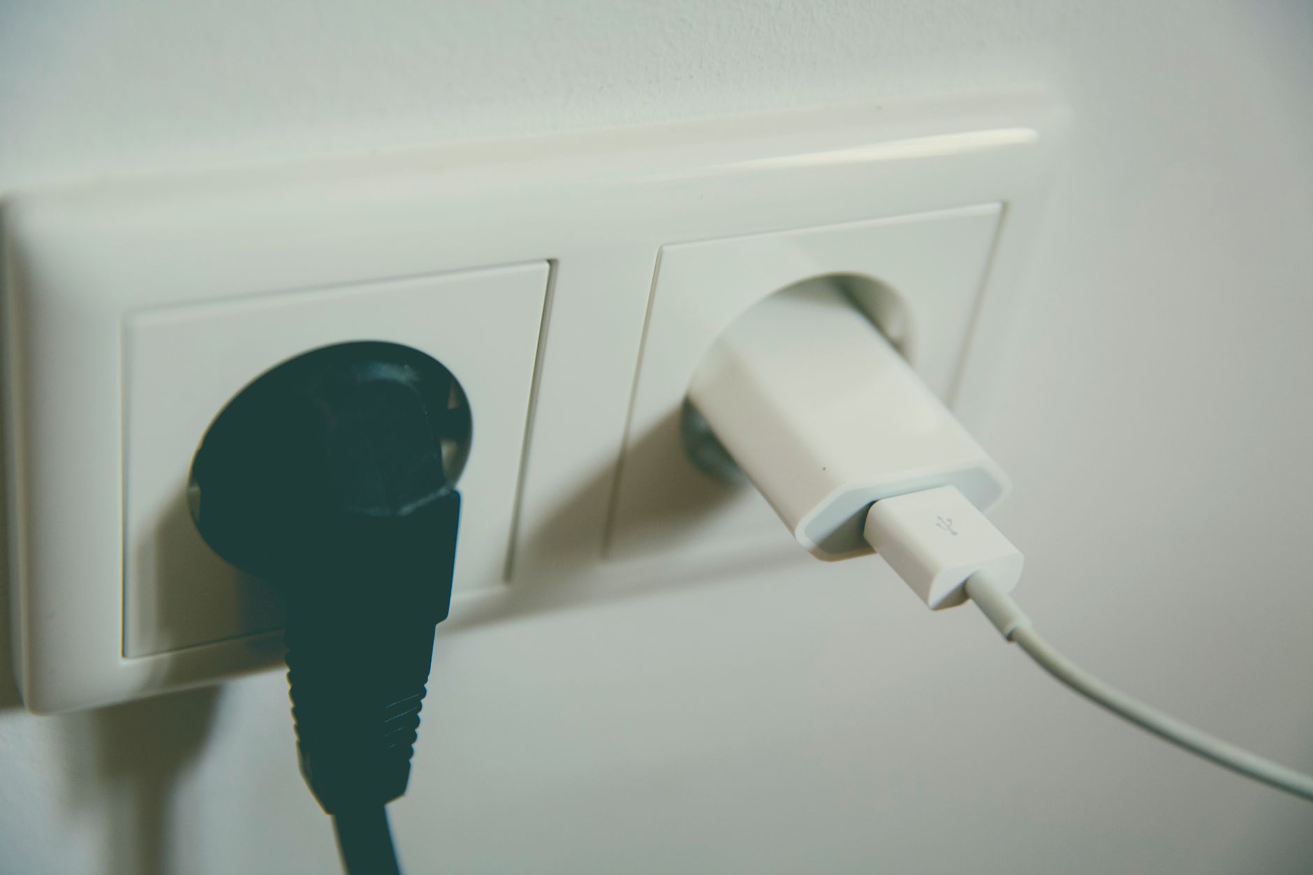 Close-up of a UK wall socket with two plugs, worth checking for scorch marks or heat before winter