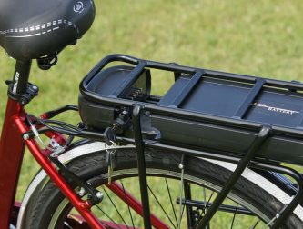 Close-up of an e-bike battery mounted on a rear rack, the kind that needs safe charging at home