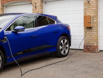 Electric car charging at home using a wall-mounted EV charge point on a driveway