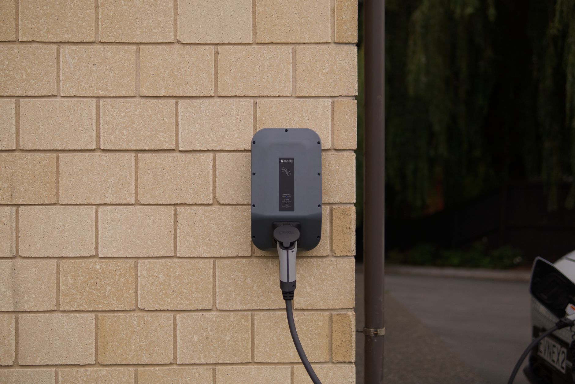 A dedicated wall-mounted electric vehicle charging point installed on a brick wall