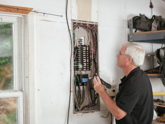 Electrician inspecting an old residential fuse box for signs it needs upgrading